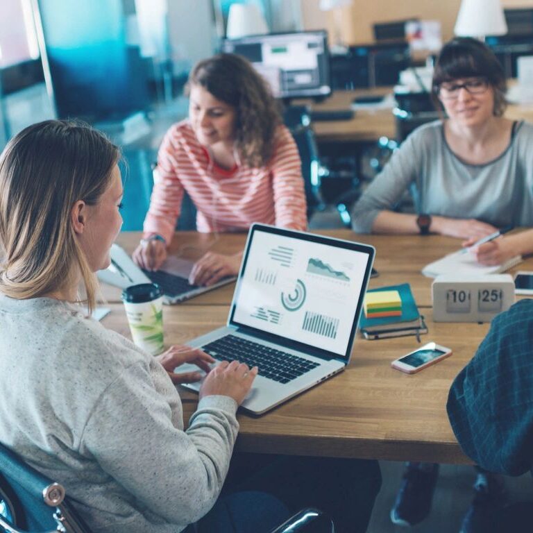 people sitting around table with computers