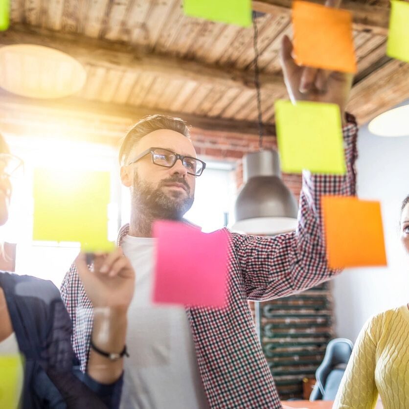 people staring at sticky notes on wall